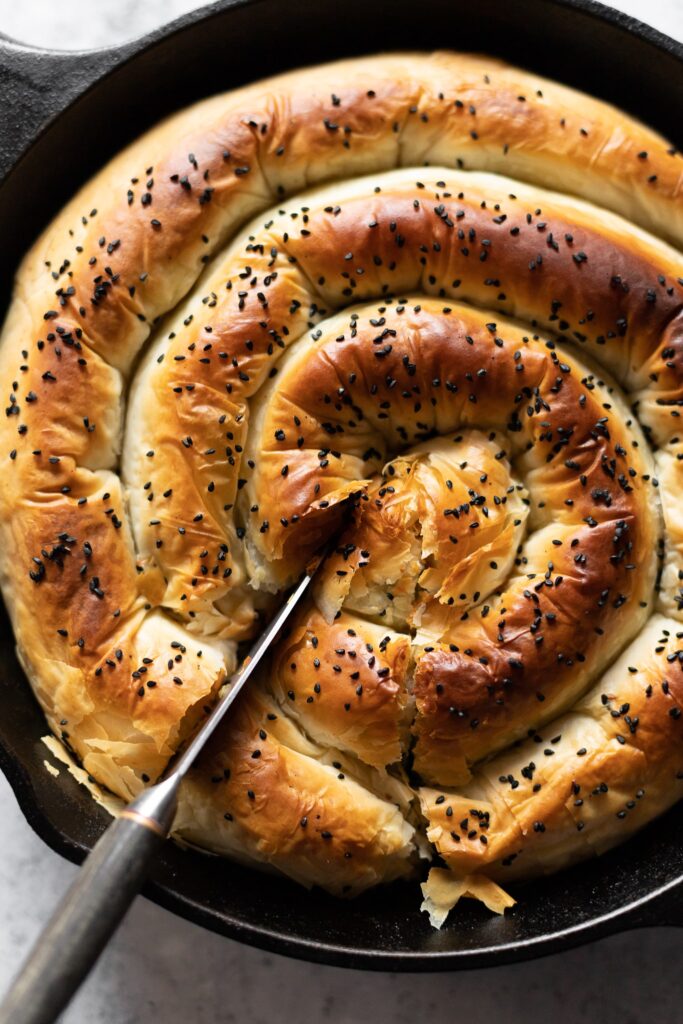 Spanakopita in a spiral with one slice about to be served, photographed from above