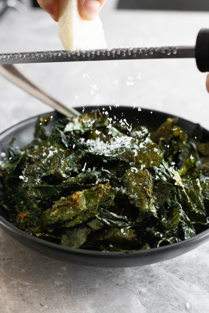 roasted kale being sprinkled with pecorino romano