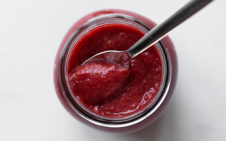 strawberry rhubarb jam in a jar with a spoon photographed from overhead