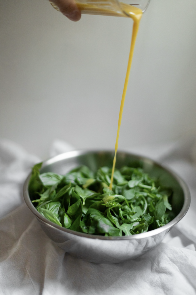 green salad with dressing being poured on